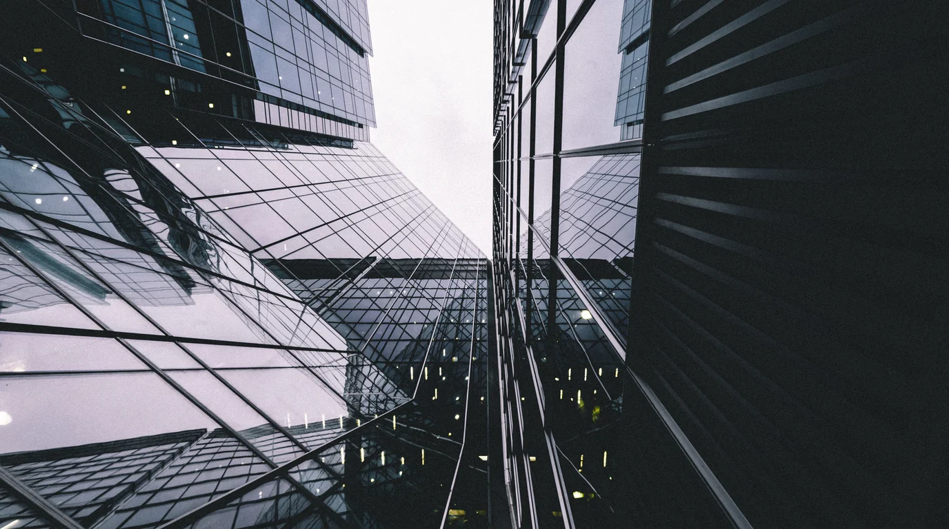Looking straight up between dark glass towers at Canary Wharf in London.