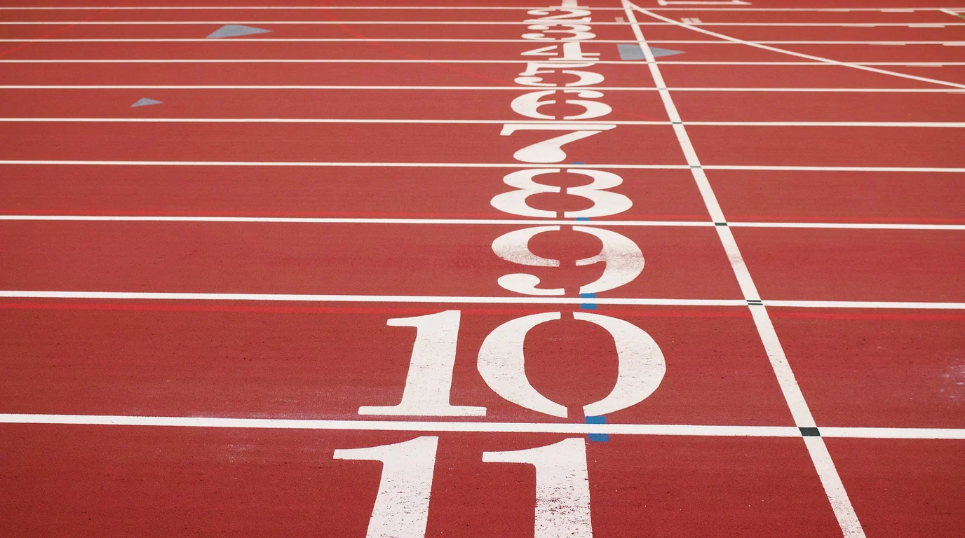 Lane numbers painted on a red running track, seen low and close.