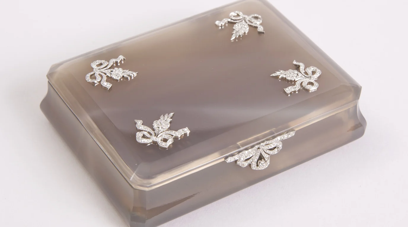 A grey agate box from around 1915, its lid decorated with small silver ribbon bows.