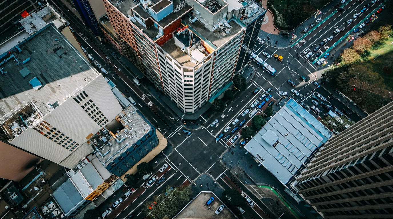 A city intersection seen straight down from above, office blocks and traffic meeting at the crossing.
