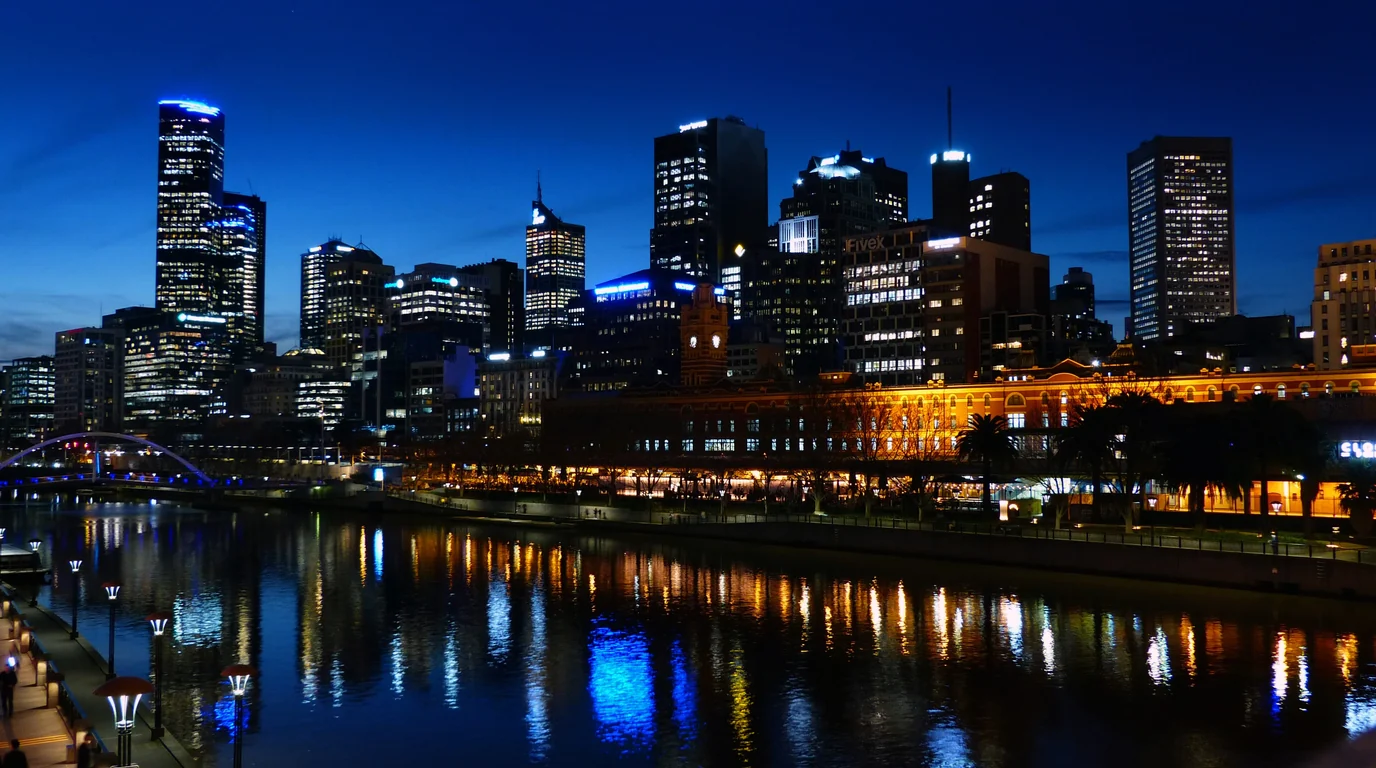 Melbourne's towers lit at blue hour, reflected in the Yarra River.