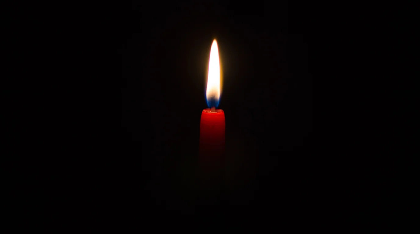A single red candle burning in darkness.