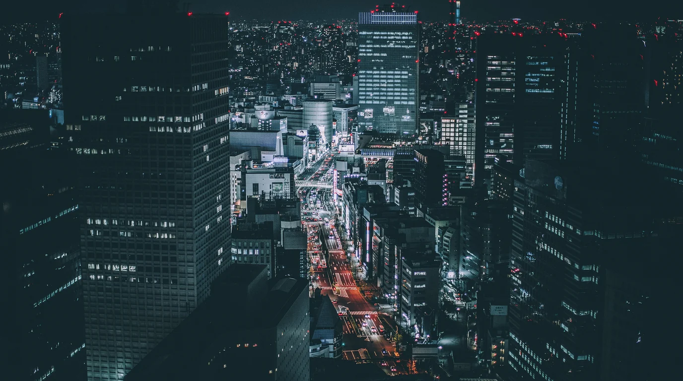 Tokyo's office towers and lit streets seen from above at night.