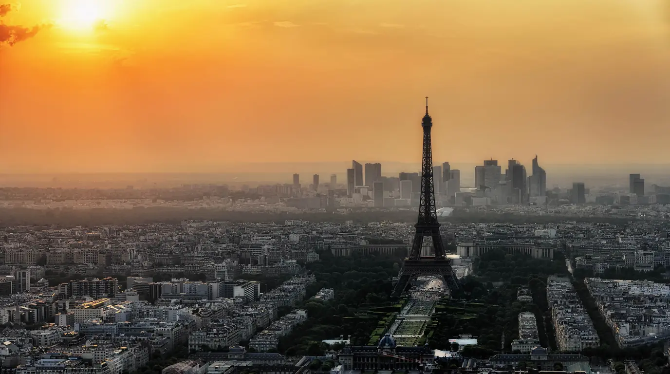 Paris at sunset from above, the Eiffel Tower in front of the La Défense business district towers