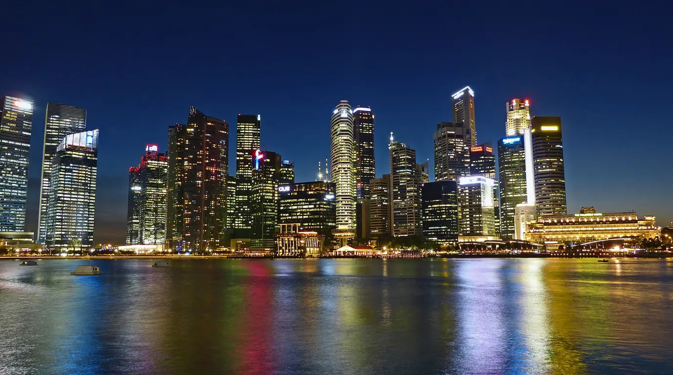 Singapore's Central Business District towers lit up at night and reflected in Marina Bay