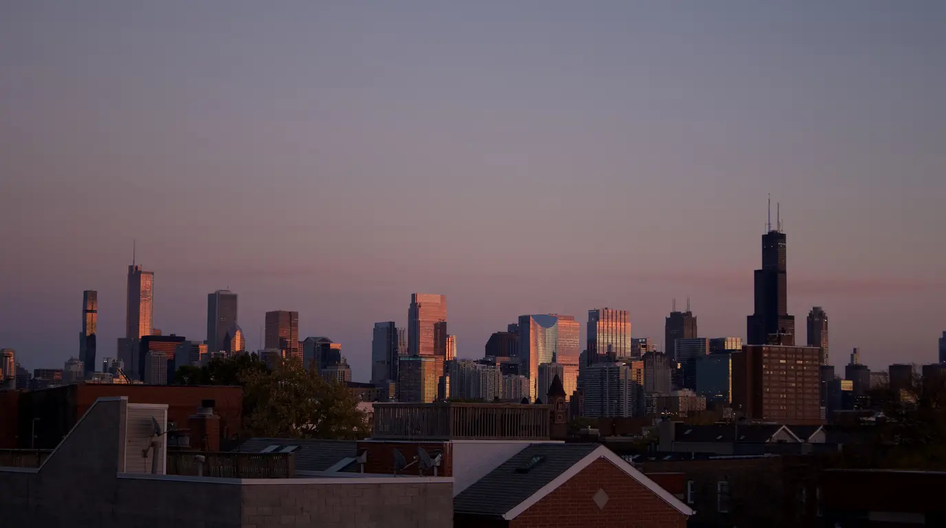 Chicago's Loop skyline at dusk, the Willis Tower on the right, above low rooftops